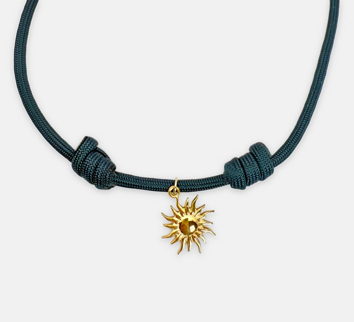 Close-up of the gold sun charm on the Isla Sol Midnight Solstice Necklace